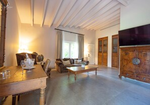 A spacious living room with a wooden coffee table, sofas, and a television. - Huerto Del Cura Hotel (Elche)