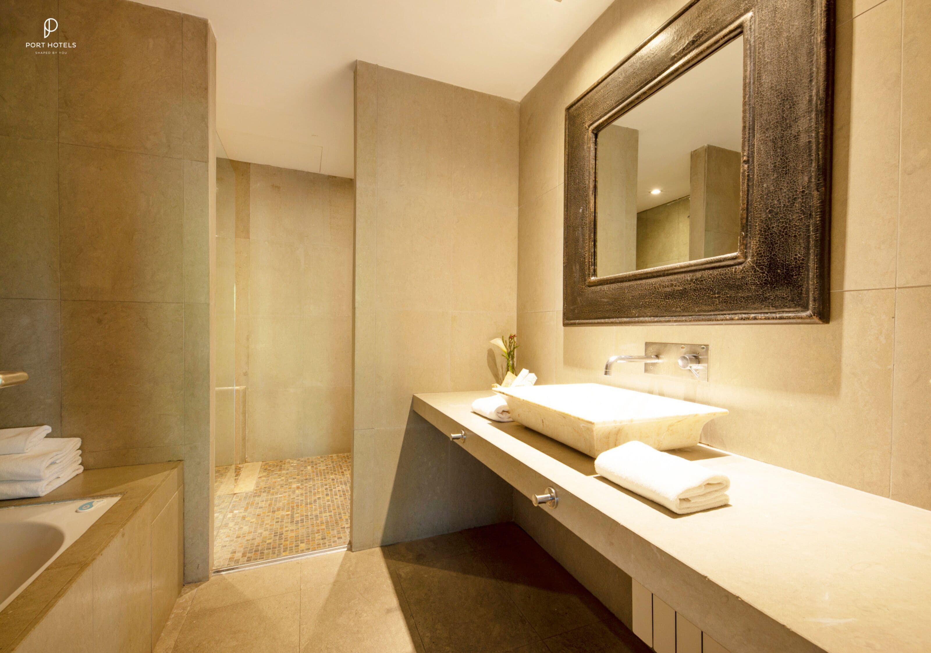 A modern bathroom with a large mirror, a sink, and a shower area.