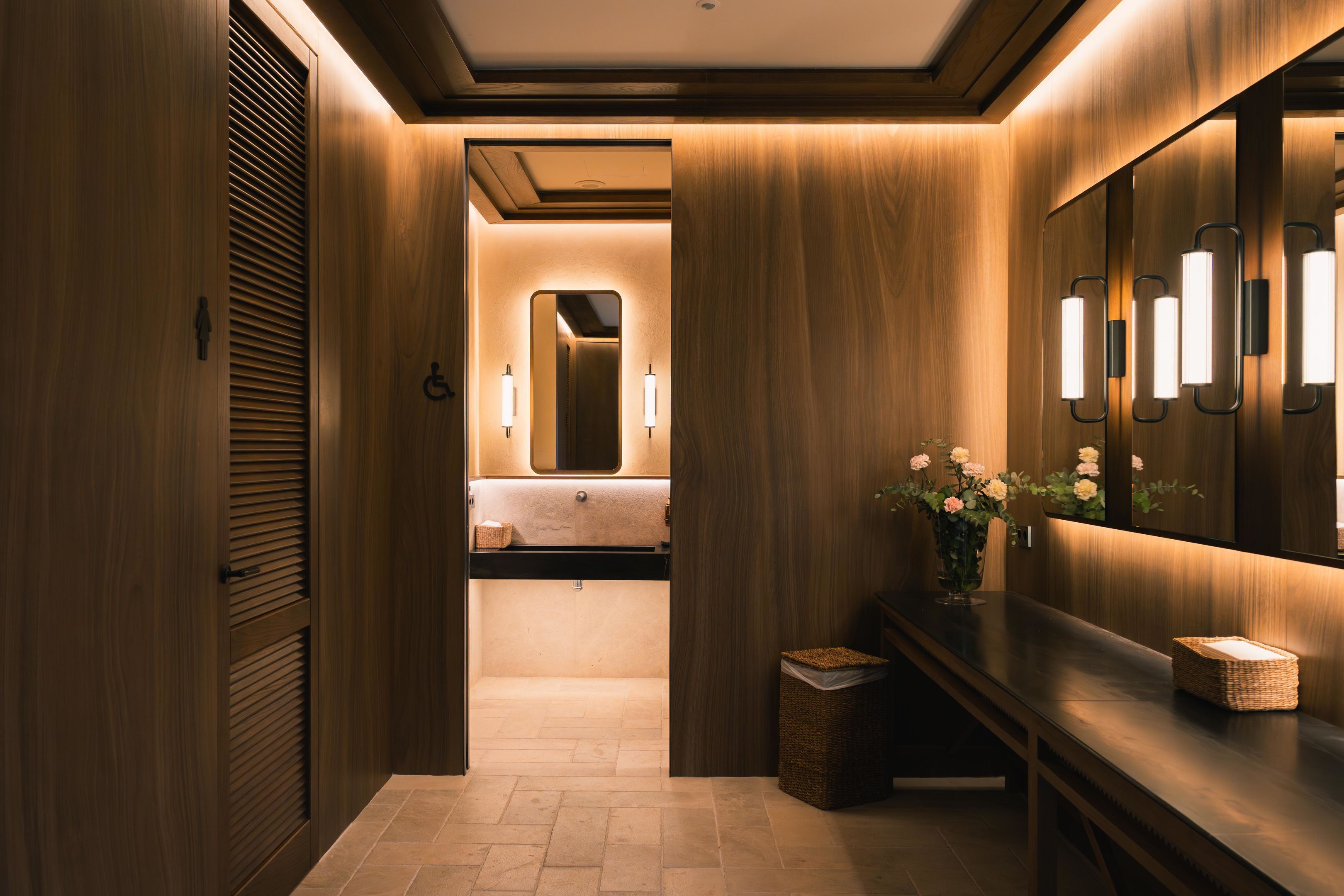 Un baño moderno con paneles de madera, un tocador con espejo y un cesto de basura.