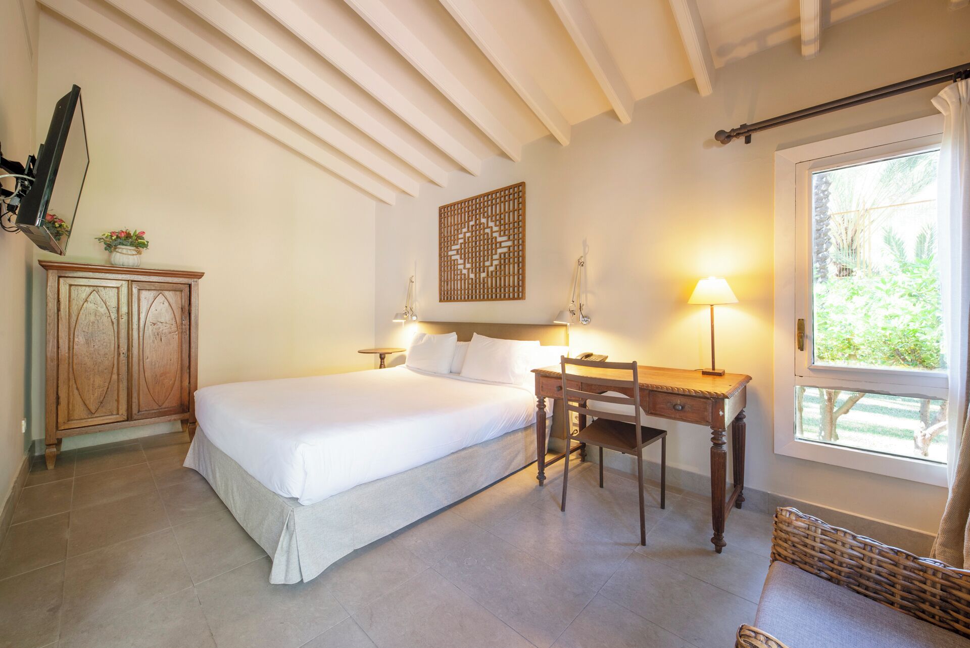 Quarto com cama, mesa de cabeceira, luminária, armário de madeira e janela com vista.