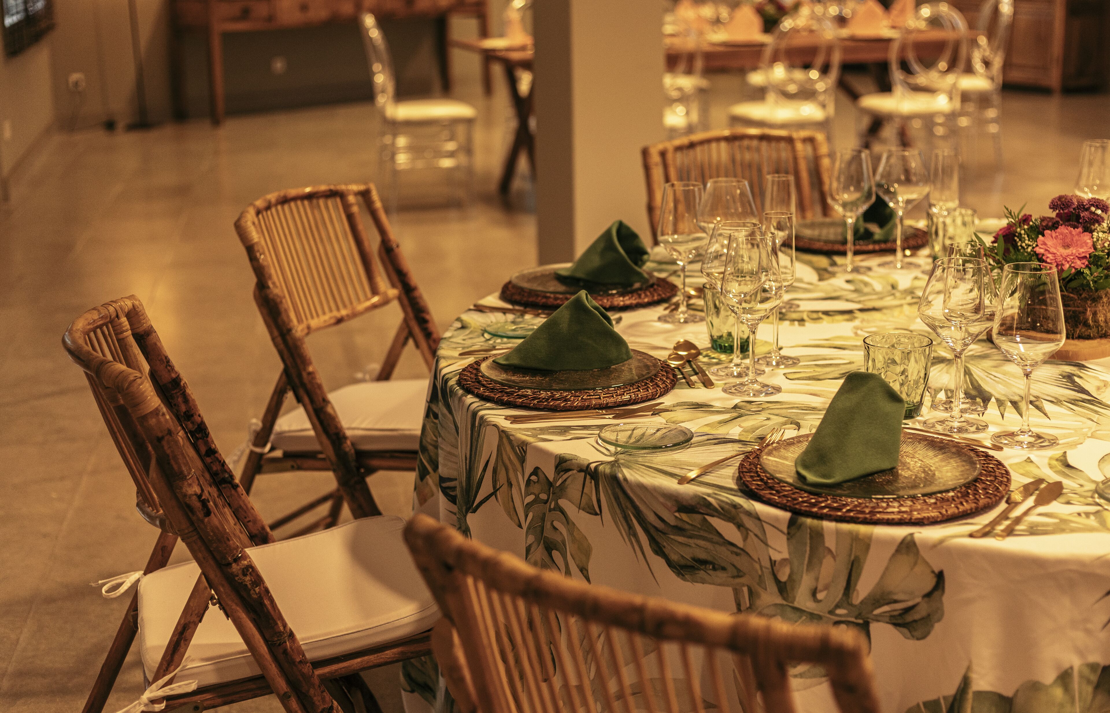 Une table à manger dressée avec des serviettes vertes, de la vaisselle transparente et un centre de table agrémenté de fleurs.