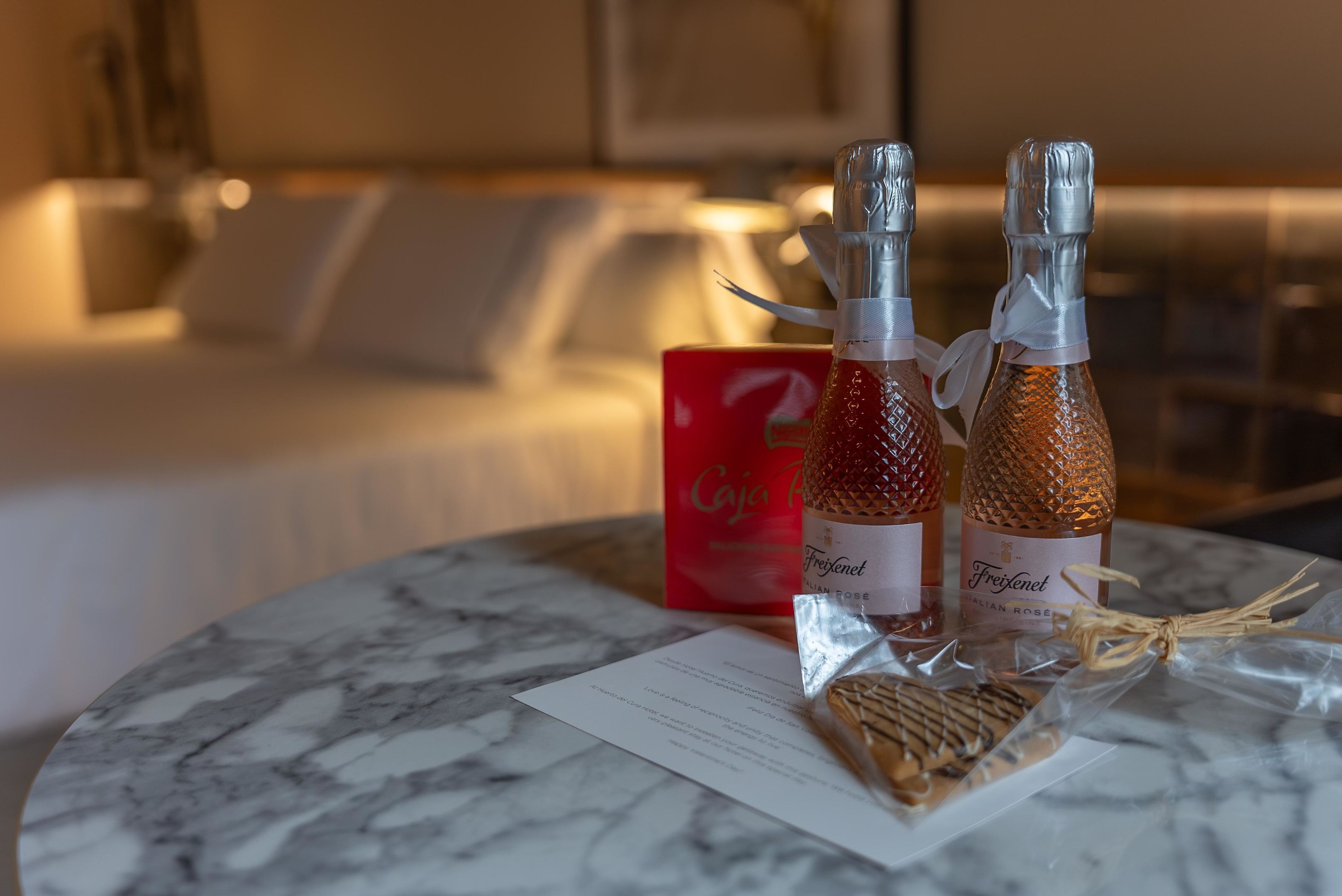 Dos botellas de Freixenet, vino espumoso, sobre una mesa de mármol con un menú y galletas.