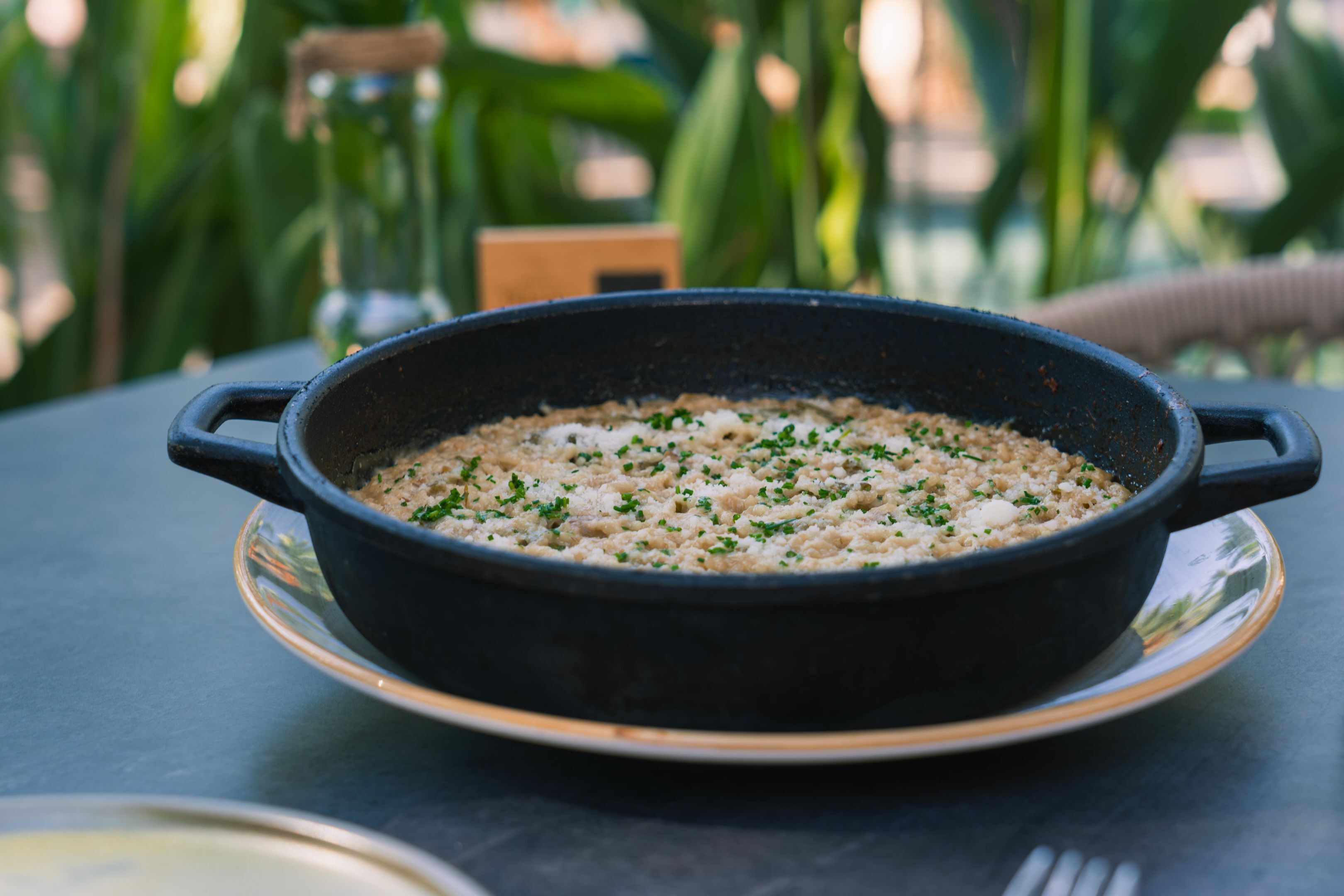 A black skillet on a saucer with a dish inside, placed on a table.