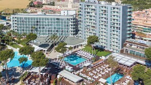 Un hotel grande con varias piscinas, zonas de estar al aire libre y una playa.