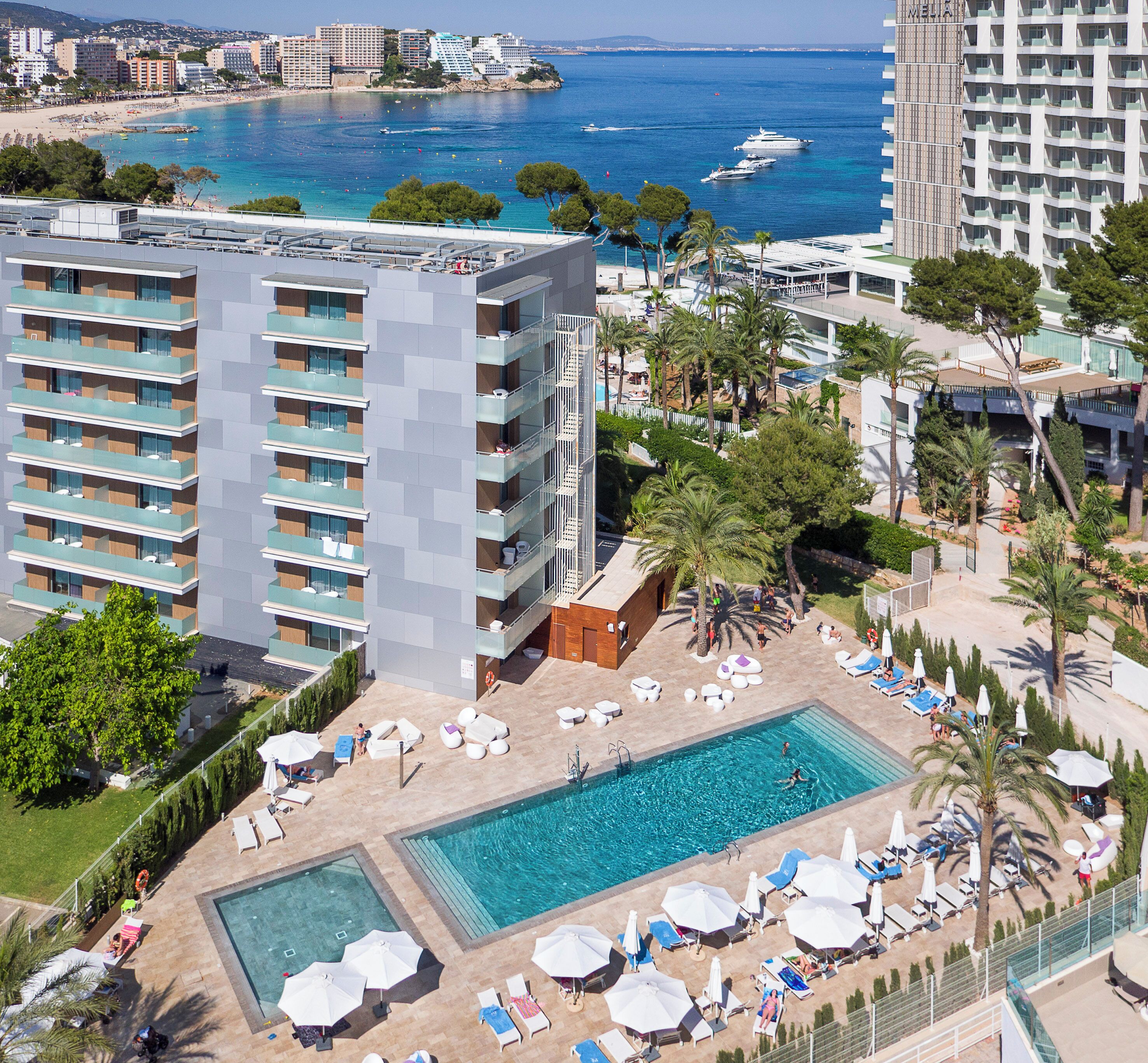 A hotel with a pool area, multiple balconies, and a view of the sea.