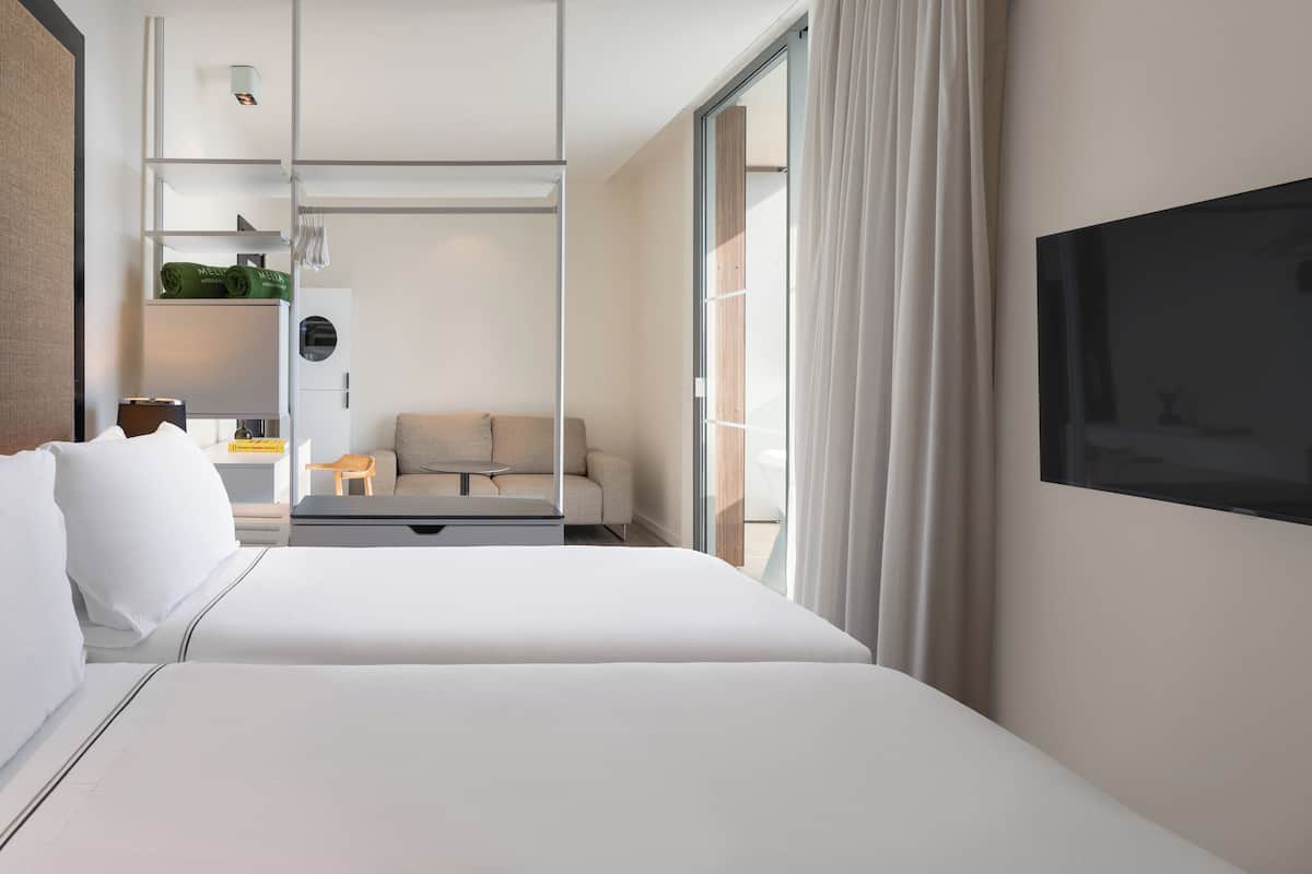 Une chambre d’hôtel moderne, dotée d’un grand lit, d’un bureau, d’un canapé et d’un téléviseur fixé au mur.