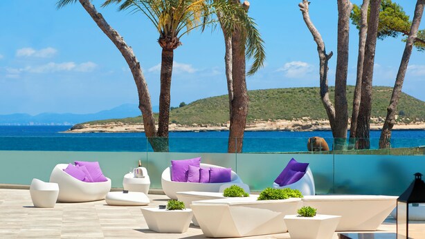 Zona de piscina con mobiliario moderno y vista al mar.