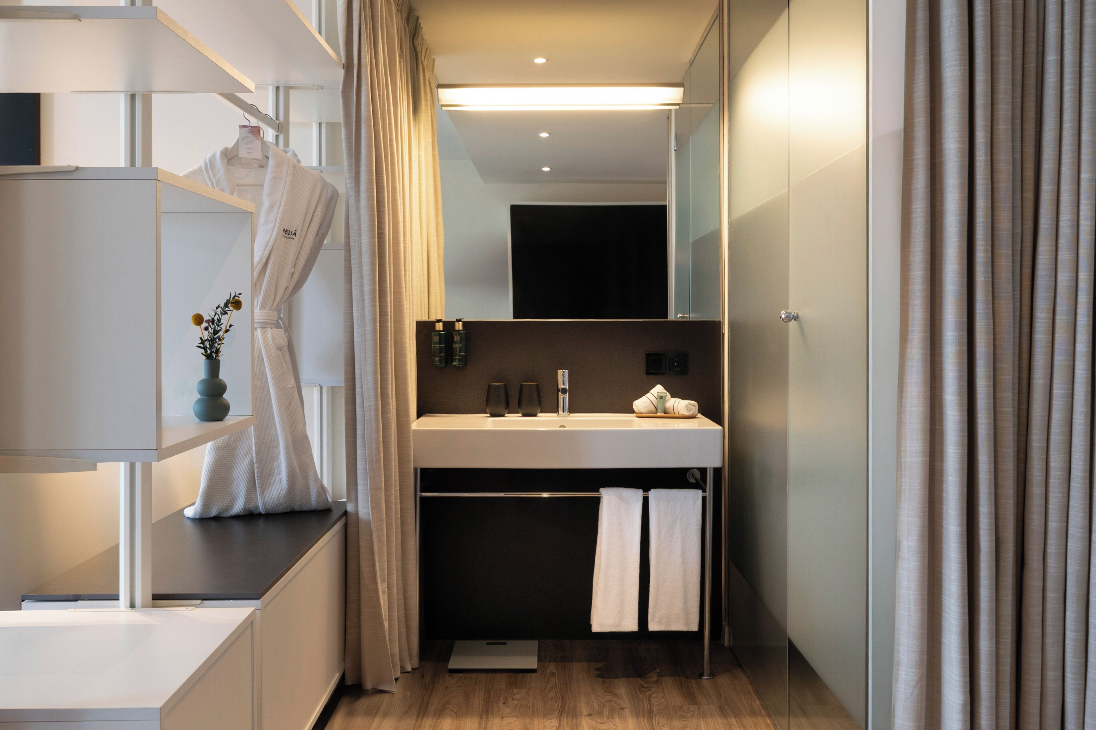 Une salle de bain moderne avec un grand miroir, un lavabo blanc et un porte-serviettes.