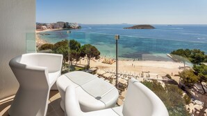 Un balcón con sillas blancas con vistas a la playa y al mar.