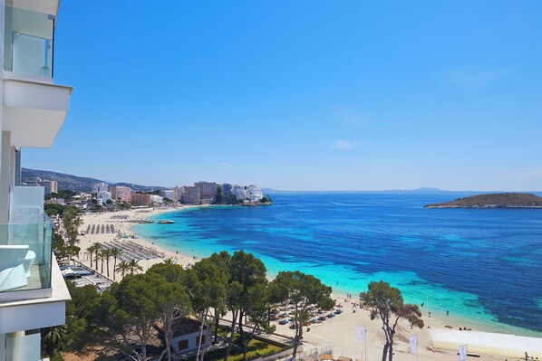 A coastal view with a beach, clear blue sea, and buildings in the background. - Melia South Beach (Calvia)
