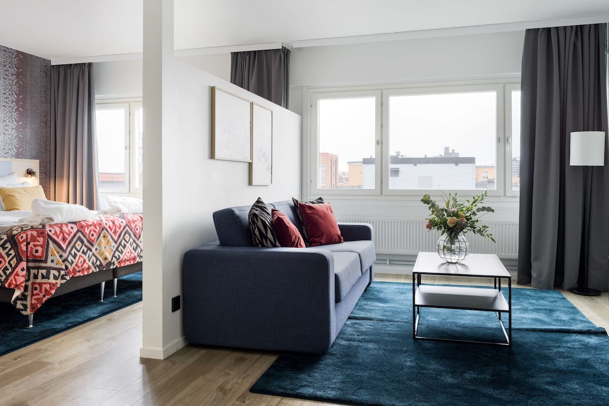 Moderni hotellihuone, jossa on sänky, sohva, sohvapöytä ja näkymä kaupunkiin.