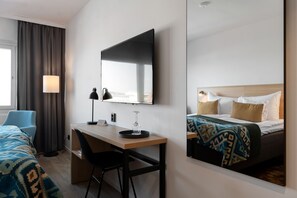 A hotel room with a bed, a desk, a chair, a lamp, and a large mirror. - Elite Hotel Brage - Hotel & Spa (Borlange)