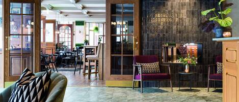 A spacious lobby with a mix of seating areas, a fireplace, and a large window providing natural light.