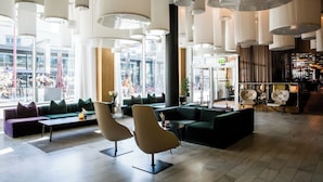A modern lobby with high ceilings, large windows, and a seating area with sofas and chairs.