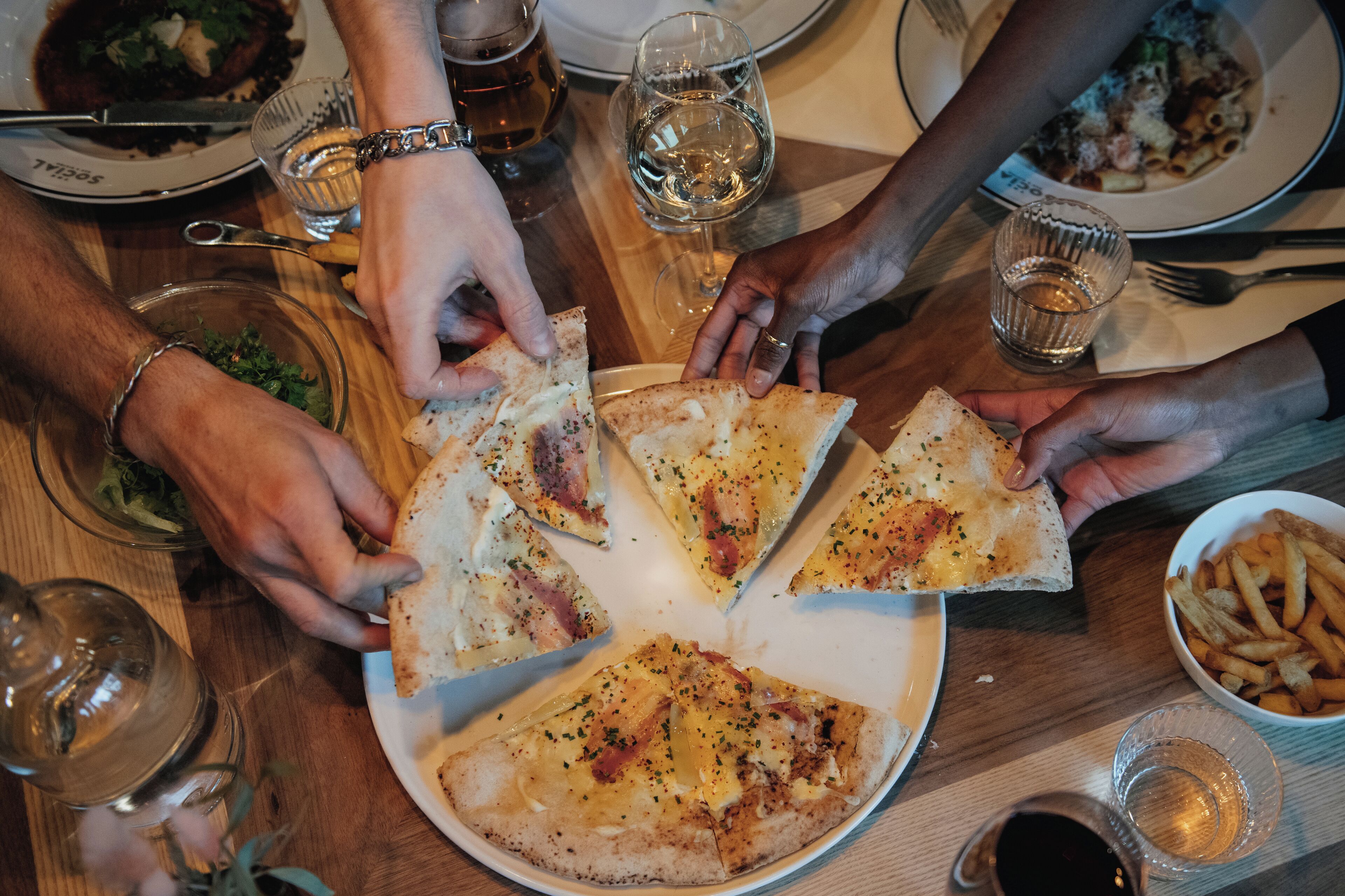 A dining table with a plate of pizza and a bowl of fries.