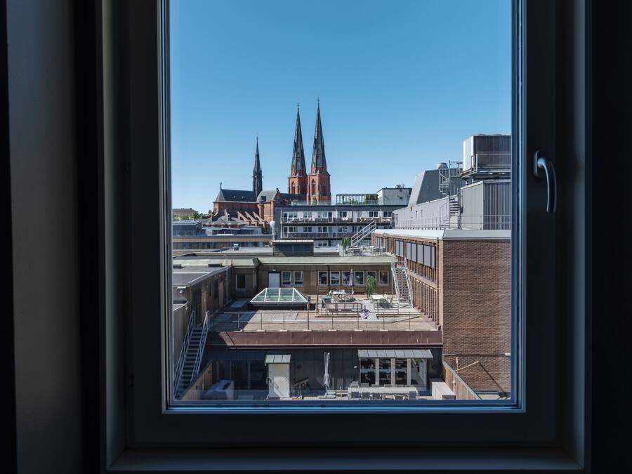 Udsigt gennem et vindue af en bygning med moderne indretning, en trappe og udsigt til en kirke med to tårne.