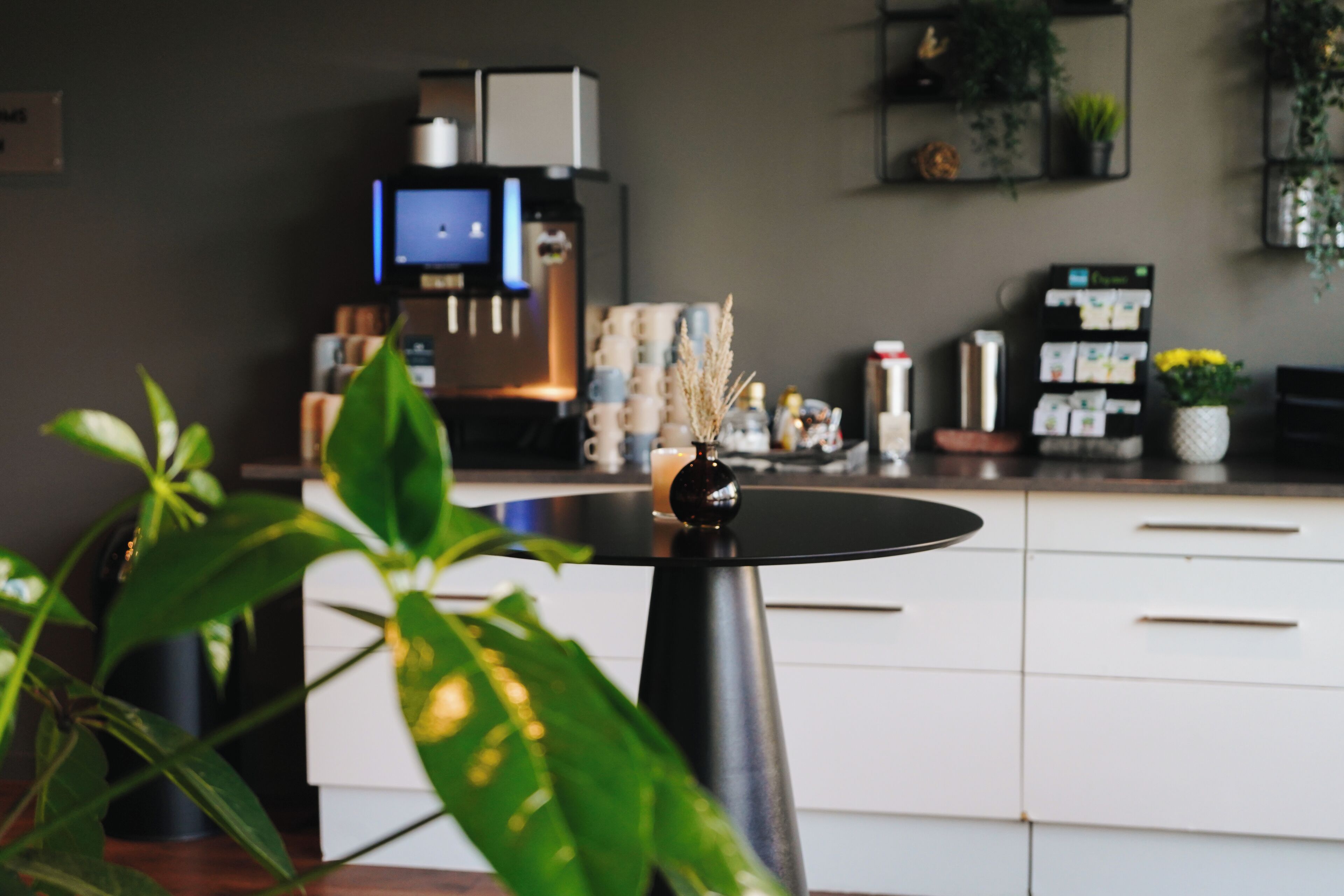Una cocina moderna con armarios blancos, encimera negra y una cafetera.