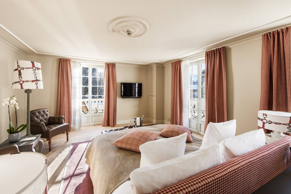 Un dormitorio amplio con una cama grande, un sofá, un televisor y vistas al balcón.