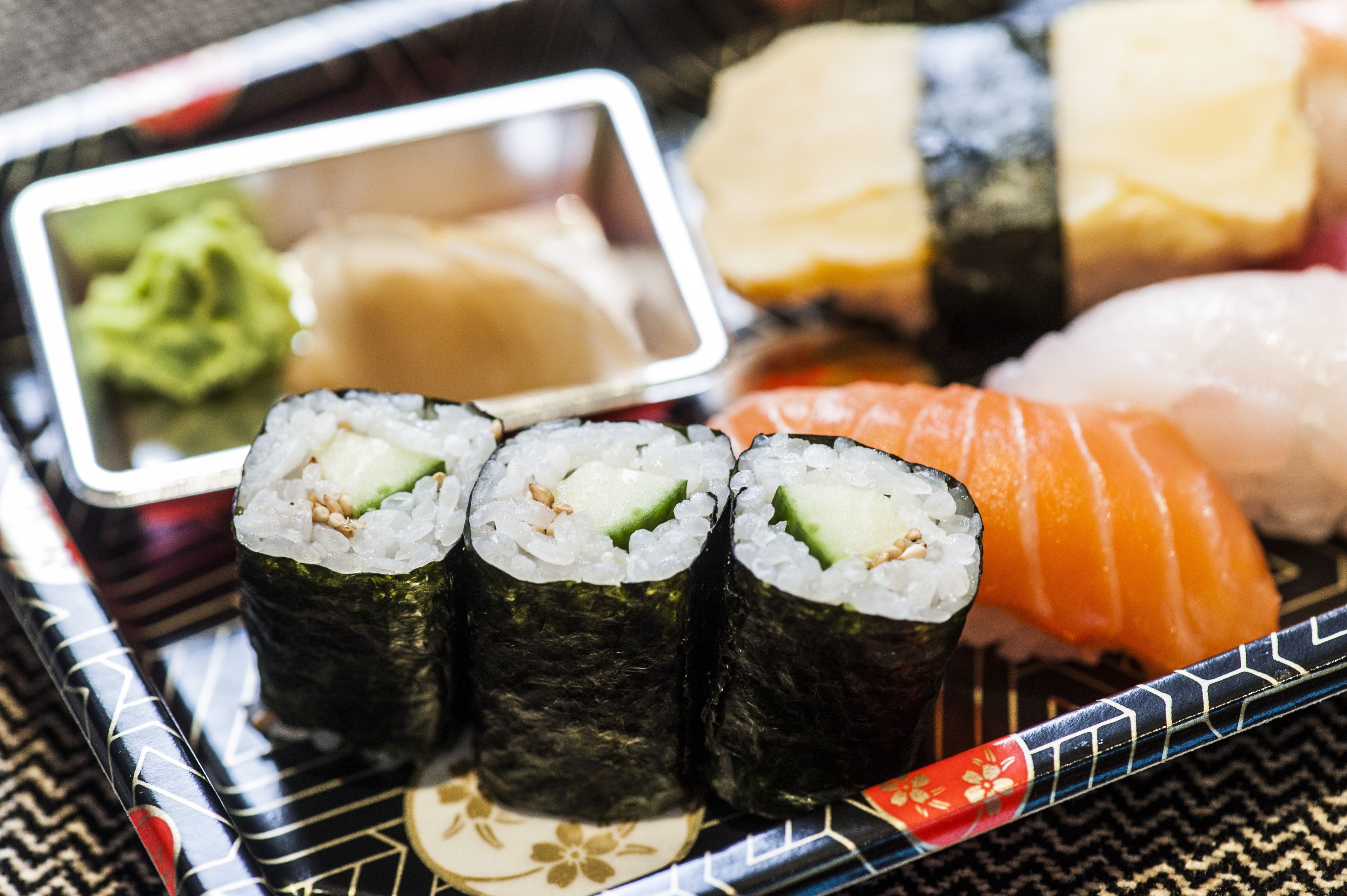 Tarjottimella on erilaisia sushilajikkeita, kuten nigiri- ja maki-sushia, ja lisäksi pieniä kulhoja, joissa on kastikkeita.