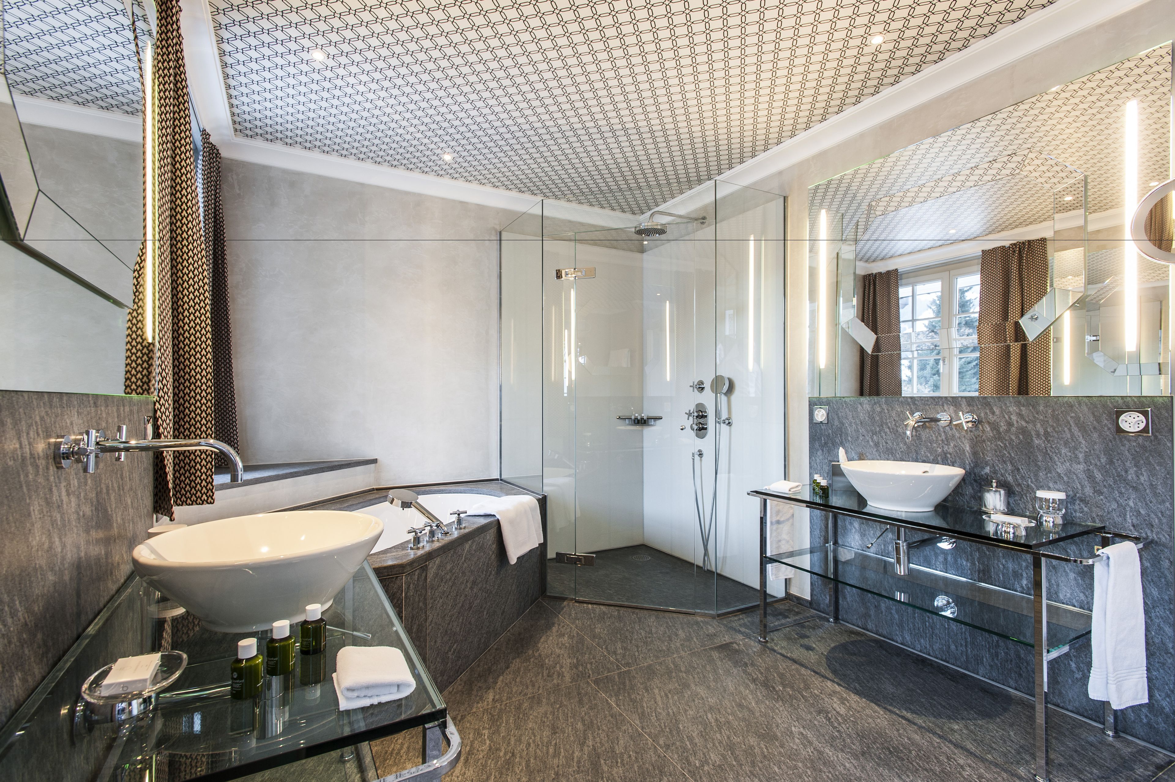 Ein modernes Badezimmer mit einer einbruchsicheren Dusche, einem großen Waschbecken und einem Marmor-Waschtisch.
