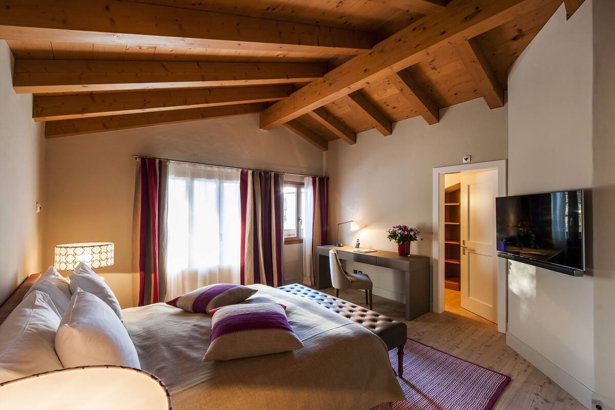 Un dormitorio con cama, escritorio, silla, televisor y armario.