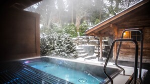 Un jacuzzi con vistas a un paisaje nevado y una cabaña de madera.