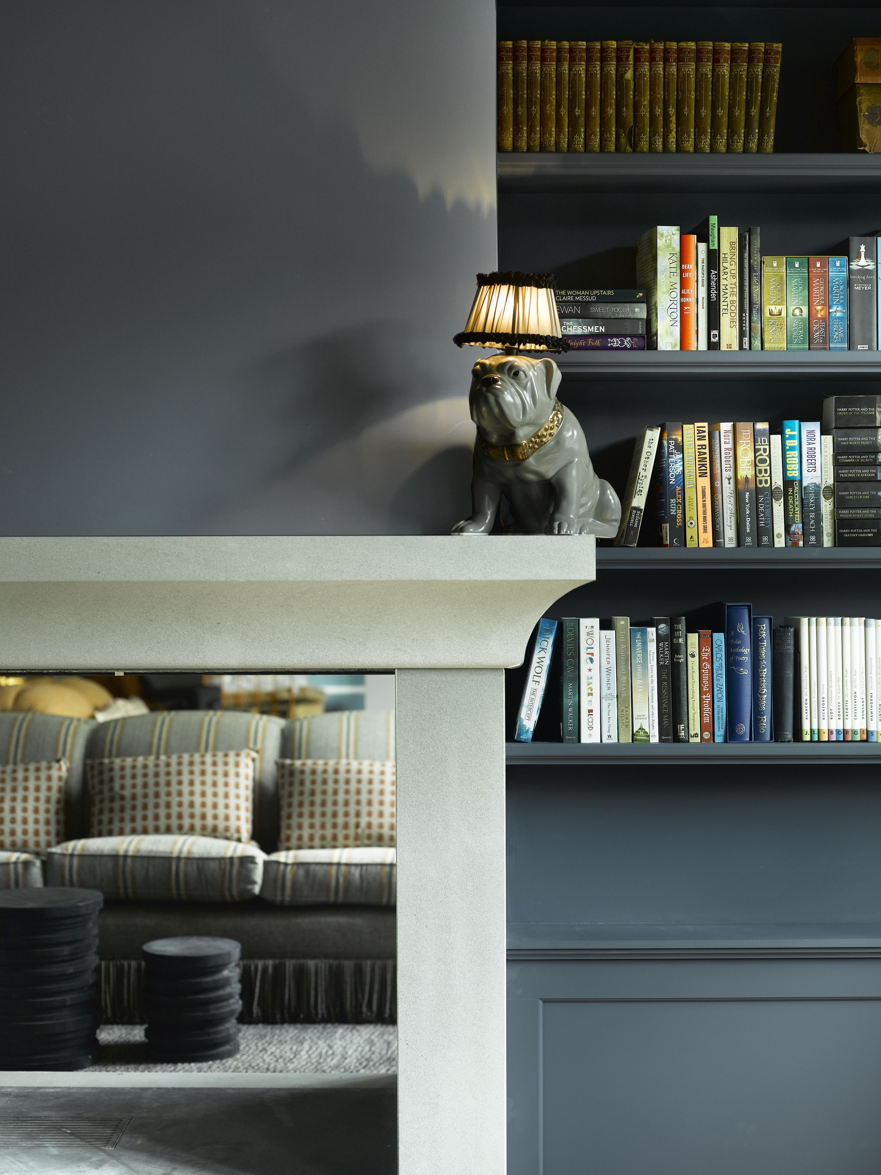A living room with a sofa, a lamp, and a bookshelf filled with books.
