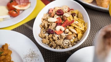 En frukostuppläggning med olika rätter, inklusive flingor, frukt och nötter.
