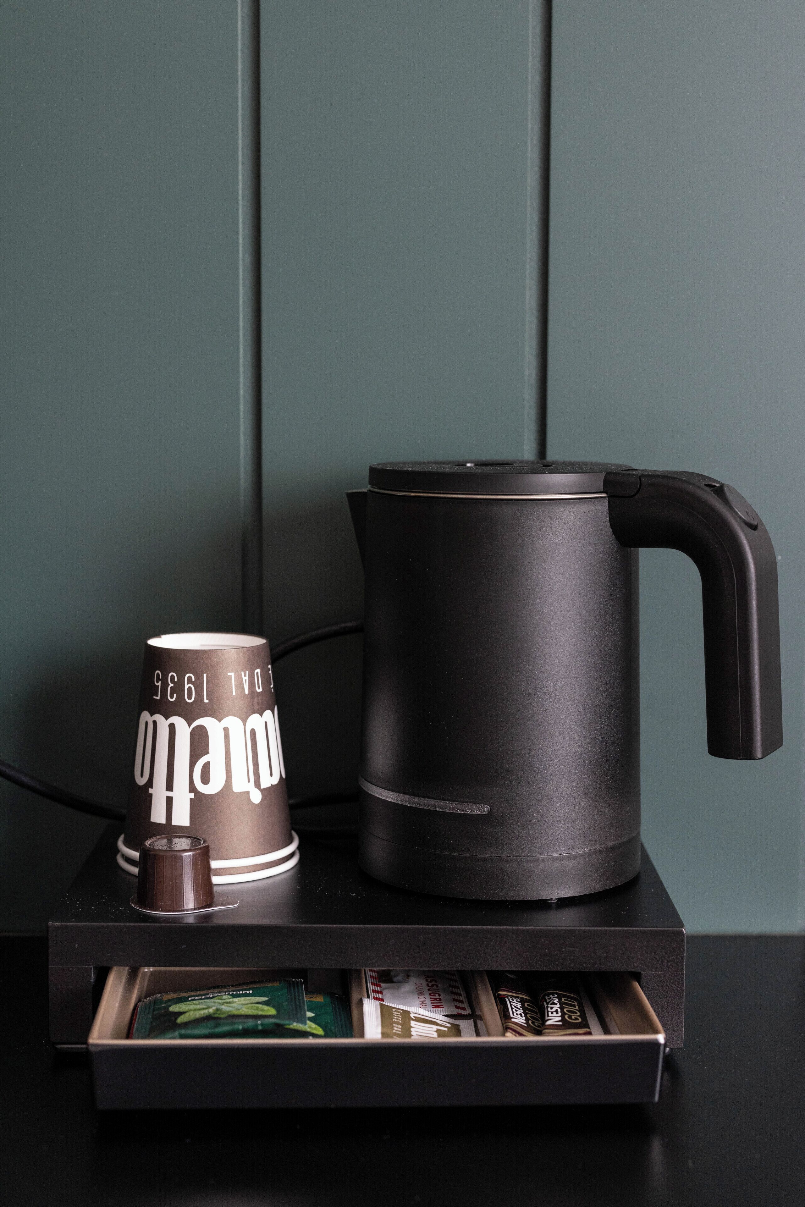 Eine Kaffeemaschine und eine Tasse auf einem schwarzen Tablett.