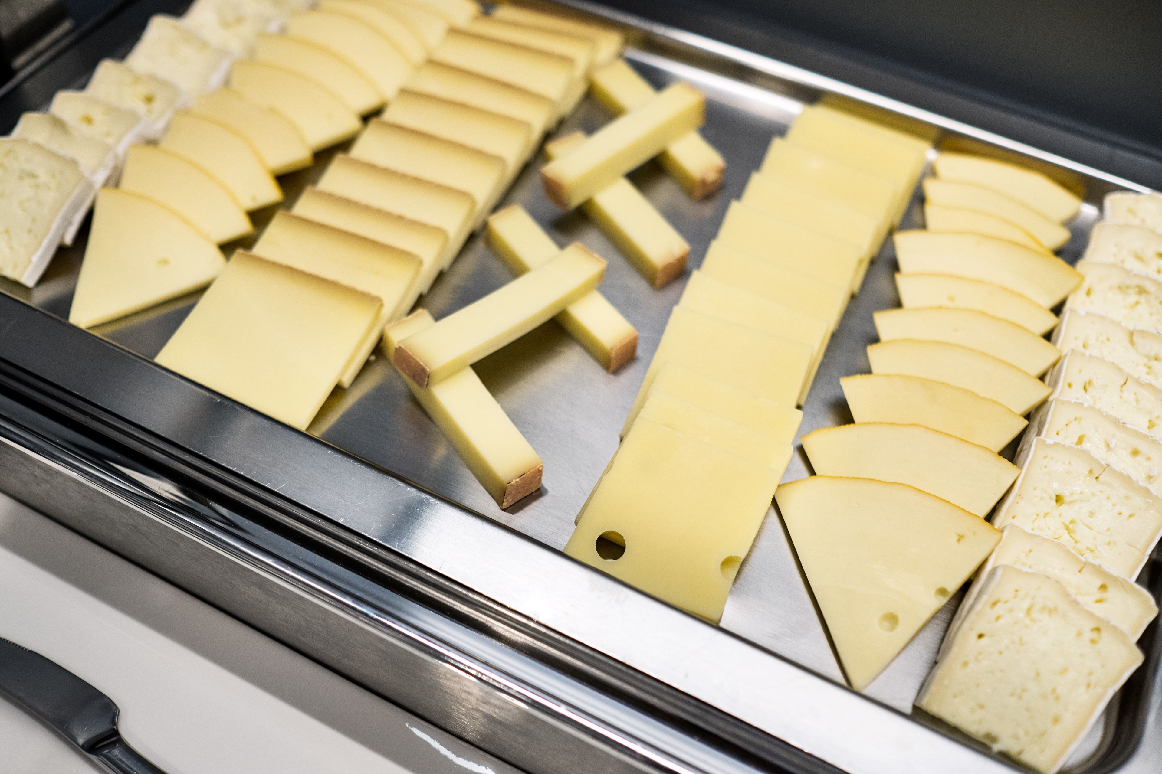 Une variété de tranches de fromage disposées sur un plateau en métal.