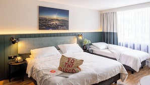 Habitación de hotel con cama, mesita de noche con lámpara, un cuadro en la pared y ventana con cortinas.