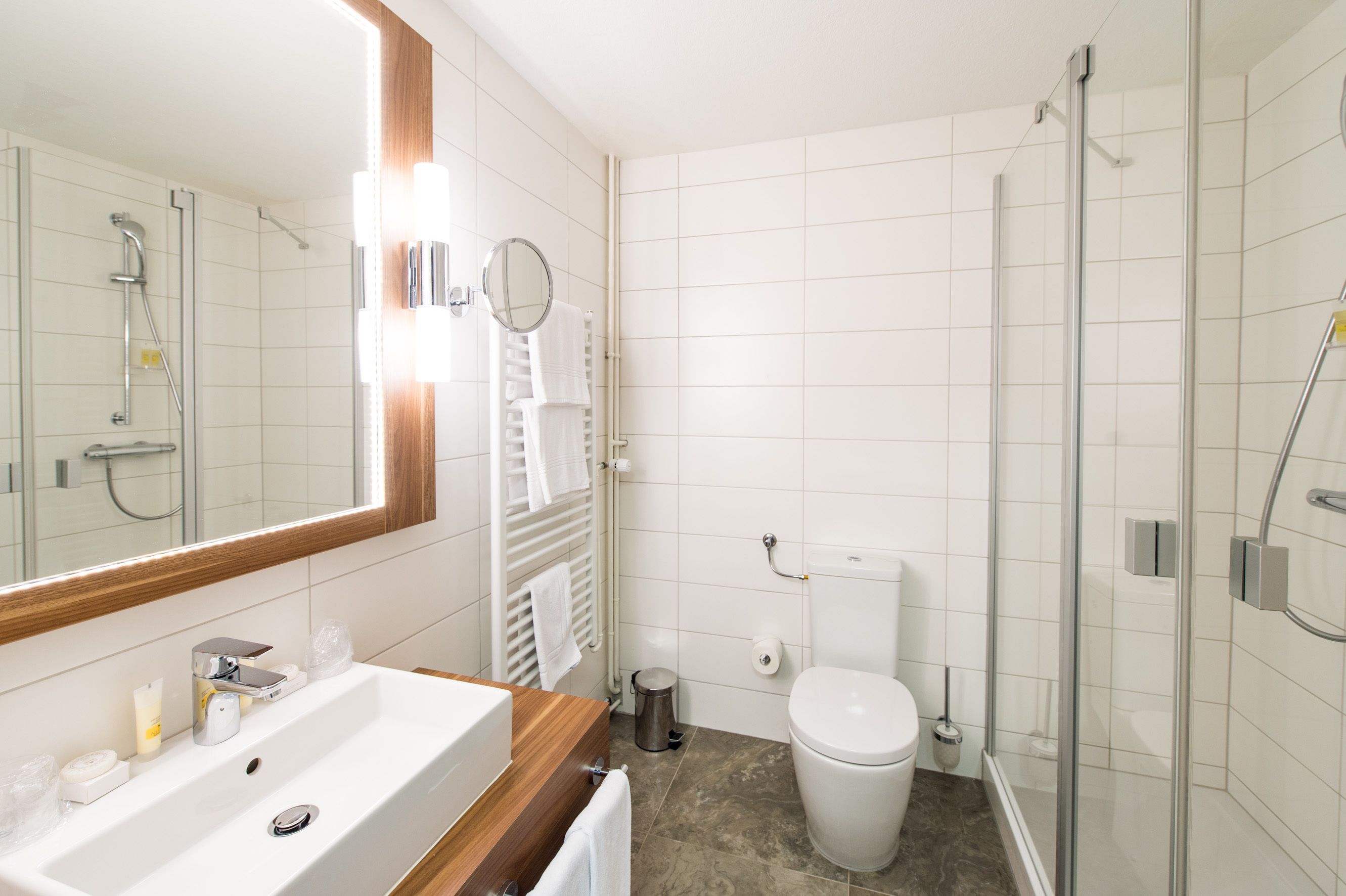 A modern bathroom with a white sink, mirror, and glass shower enclosure.