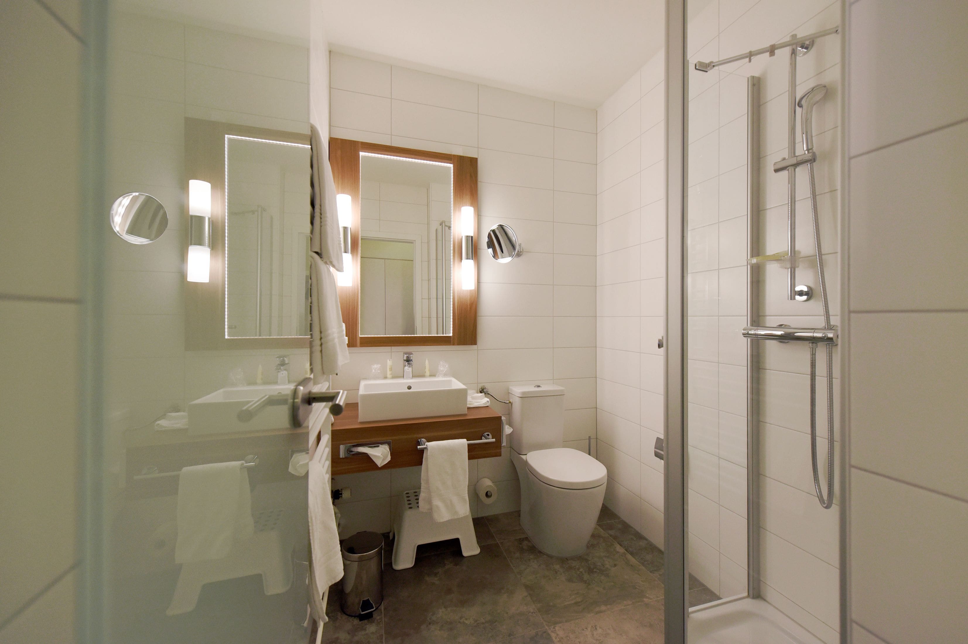 A modern bathroom with a glass shower enclosure, a sink with a mirror, and a toilet.