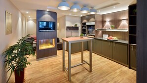 Una cocina moderna con armarios de madera, una isla central, iluminación colgante y un televisor de pantalla plana.