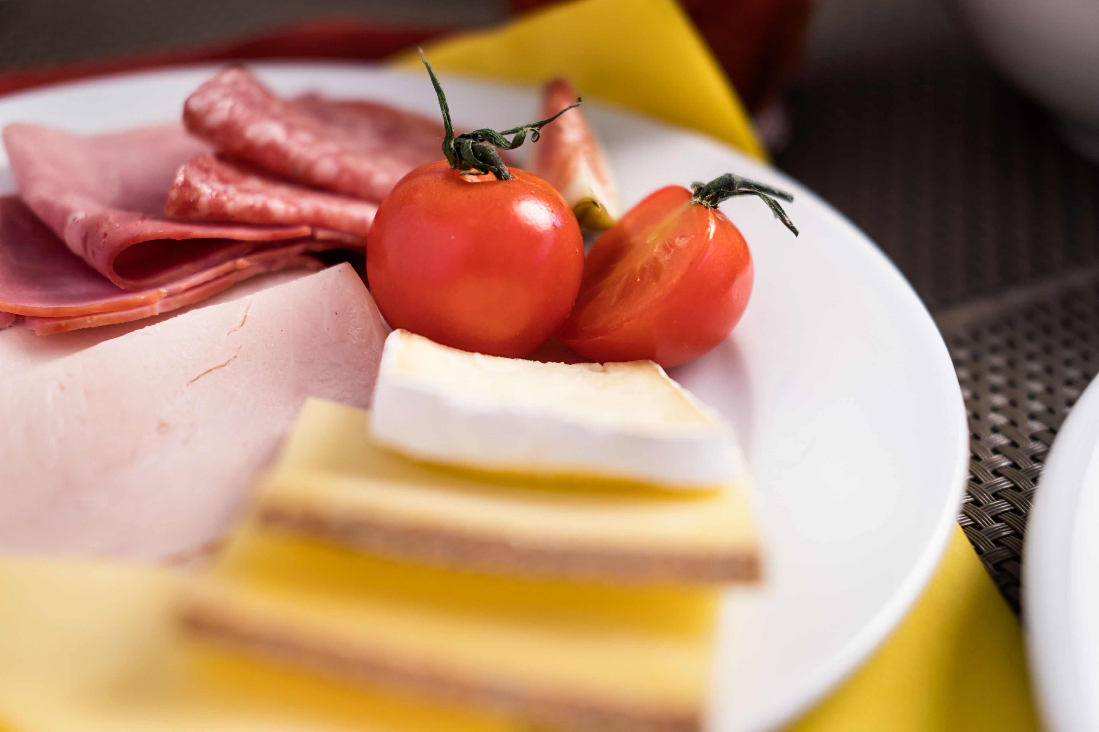Ein Teller mit Scheibchen von Schinken, Käse und Tomaten.