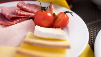 Ein Teller mit Scheibchen von Schinken, Käse und Tomaten.