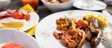 A breakfast setting with various dishes including eggs, bacon, sausages, and toast.