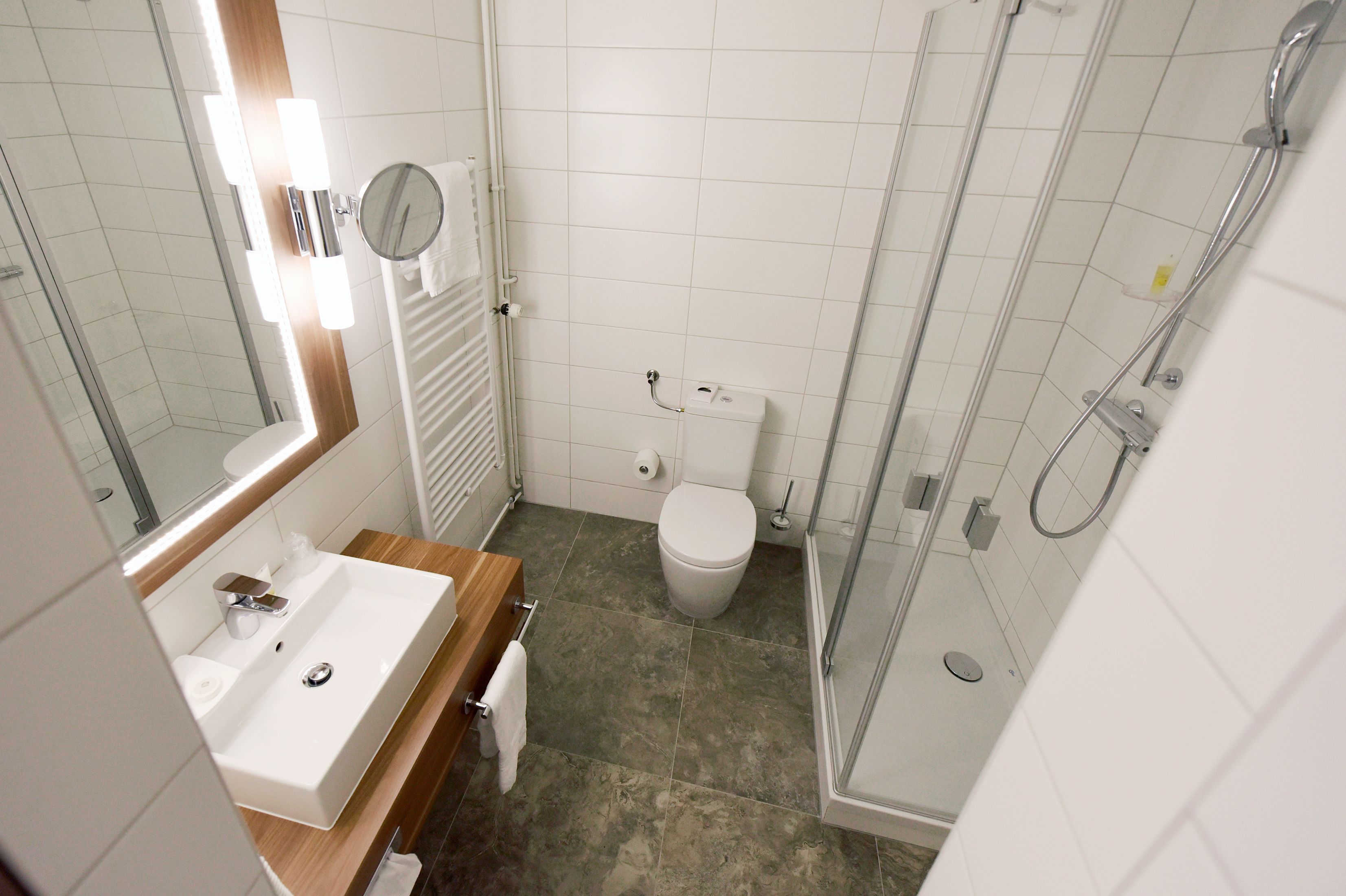 Ein modernes Badezimmer mit Waschbecken, Spiegel, Toilette und Dusche.
