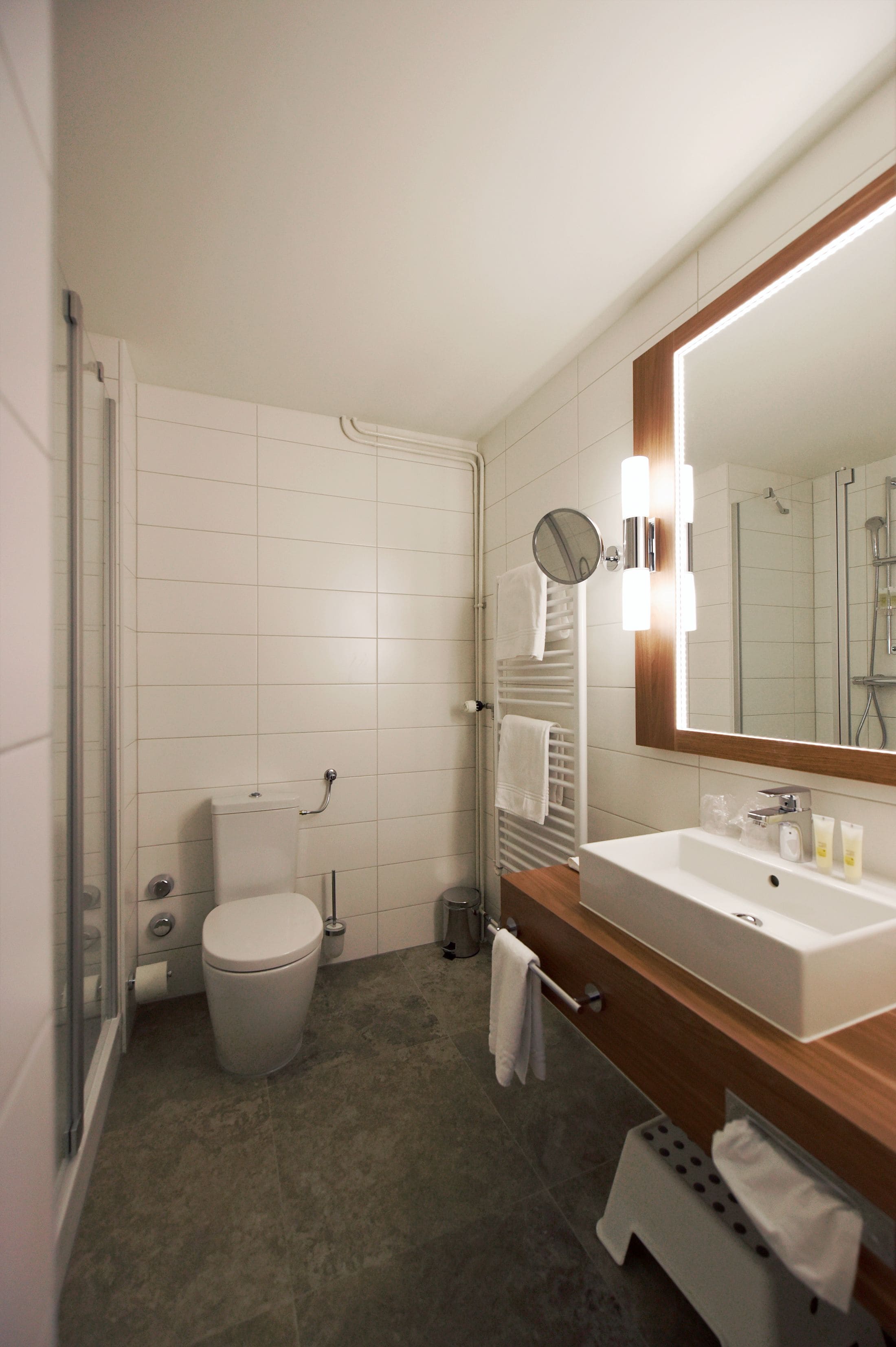 A modern bathroom with a toilet, sink, and mirror.