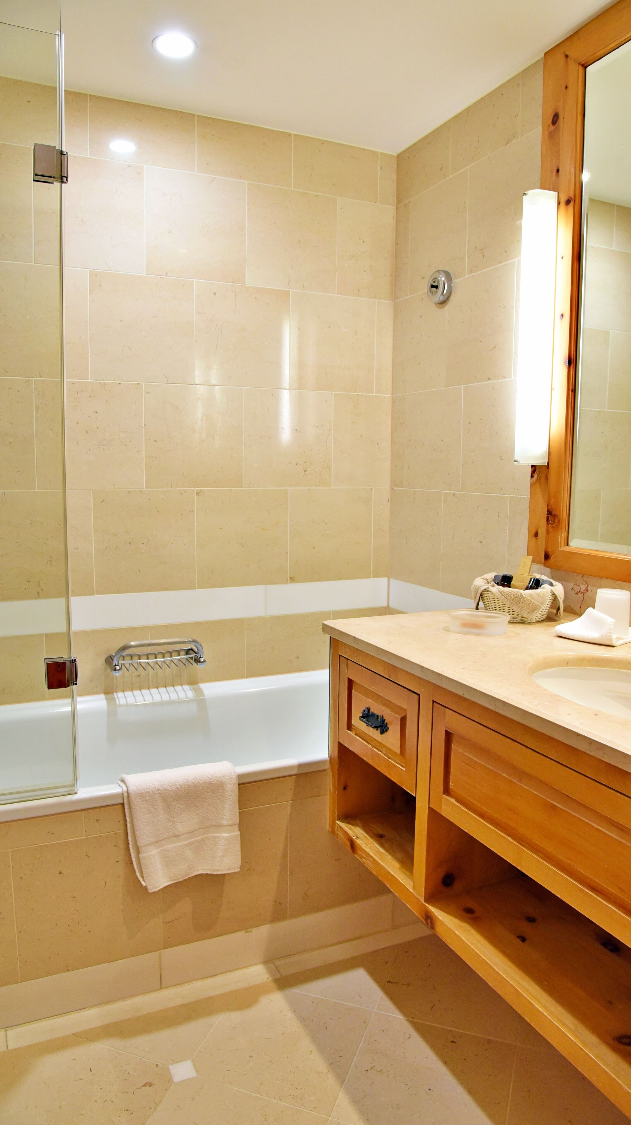 Un baño moderno con bañera, tocador de madera y un espejo grande.