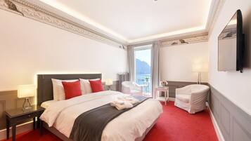 Une chambre d’hôtel avec un grand lit, un bureau, une chaise, une télévision et une vue sur la mer.