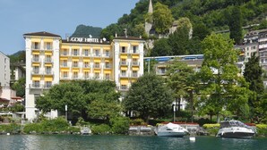 Un hotel con varios balcones, un letrero llamativo y vistas al agua y la vegetación.