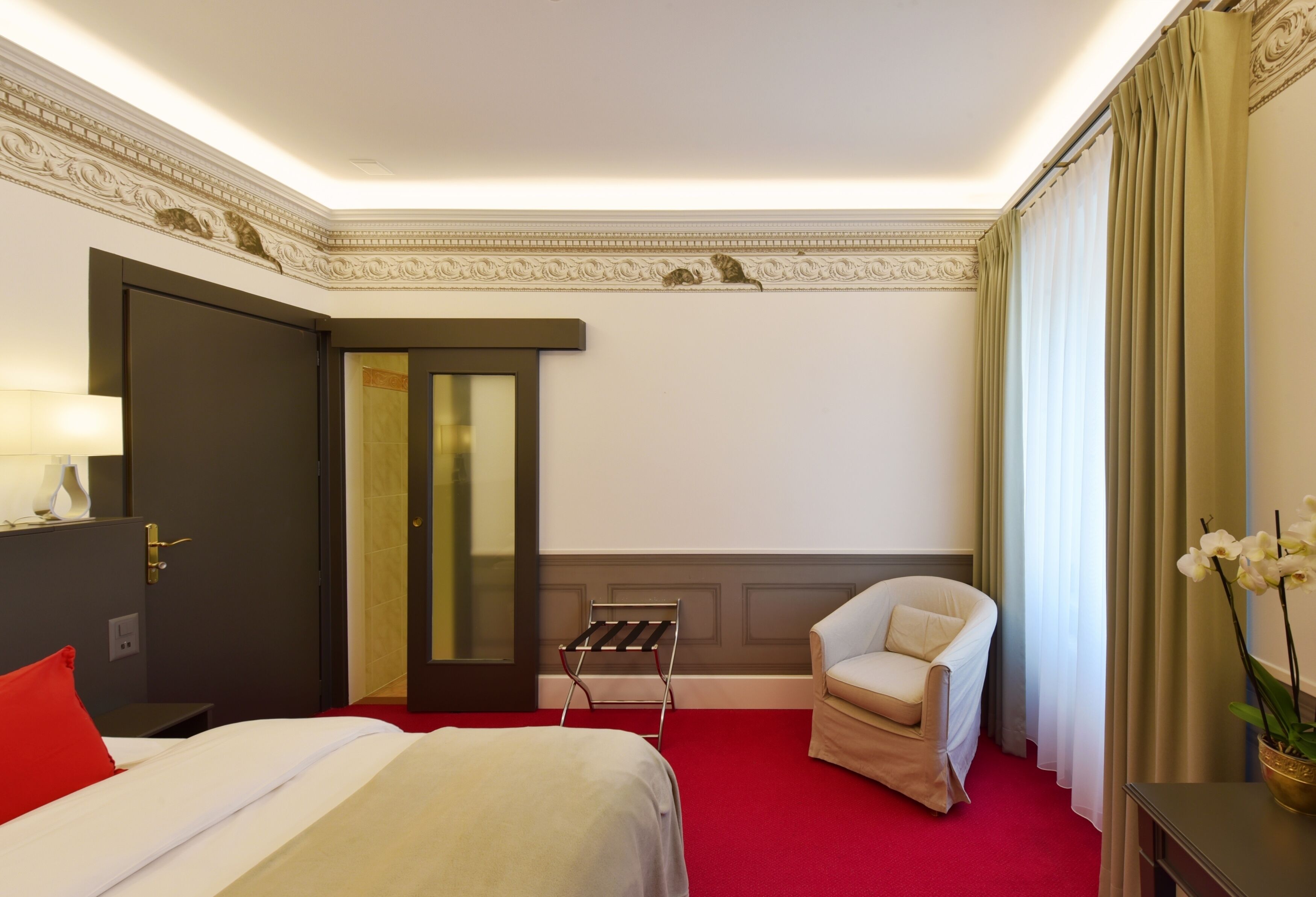 A hotel room with a bed, a chair, a desk, and a window with curtains.