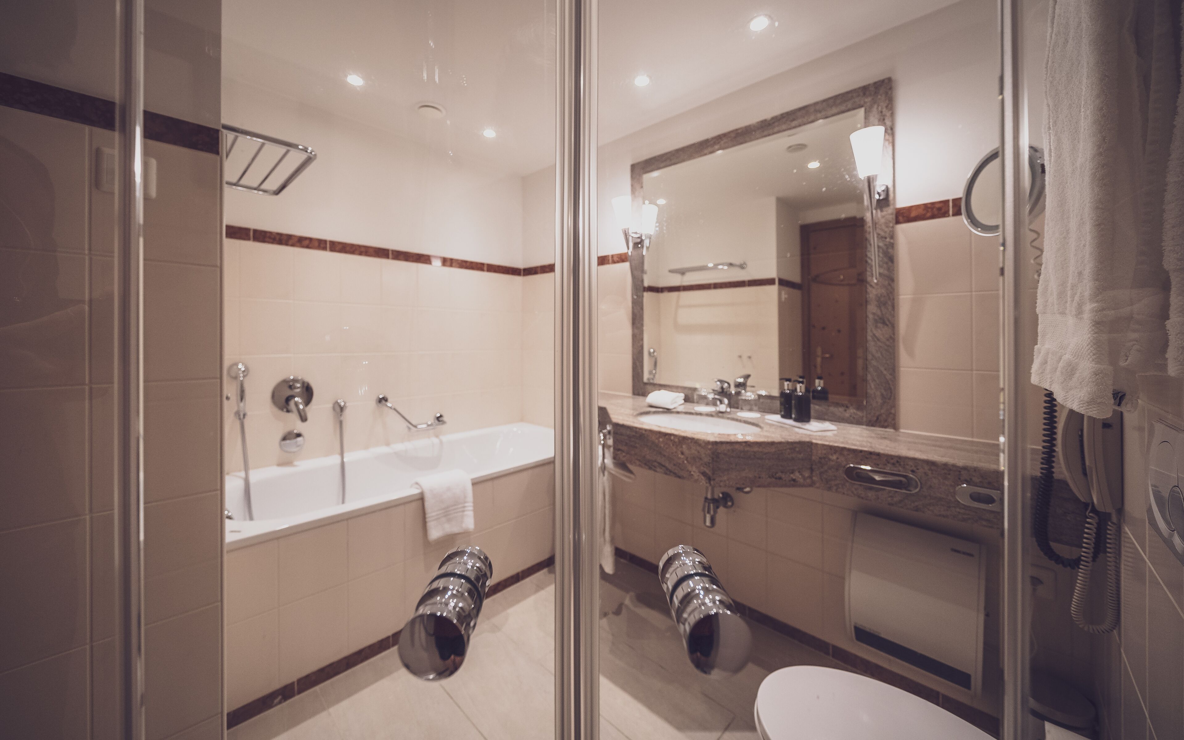 A modern bathroom with a glass-enclosed shower, a bathtub, a sink with a mirror, and a toilet.