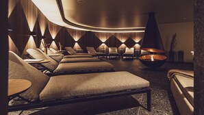 A modern spa room with multiple massage chairs, a central fire feature, and ambient lighting. - Hotel Waldhuus Davos (Davos)