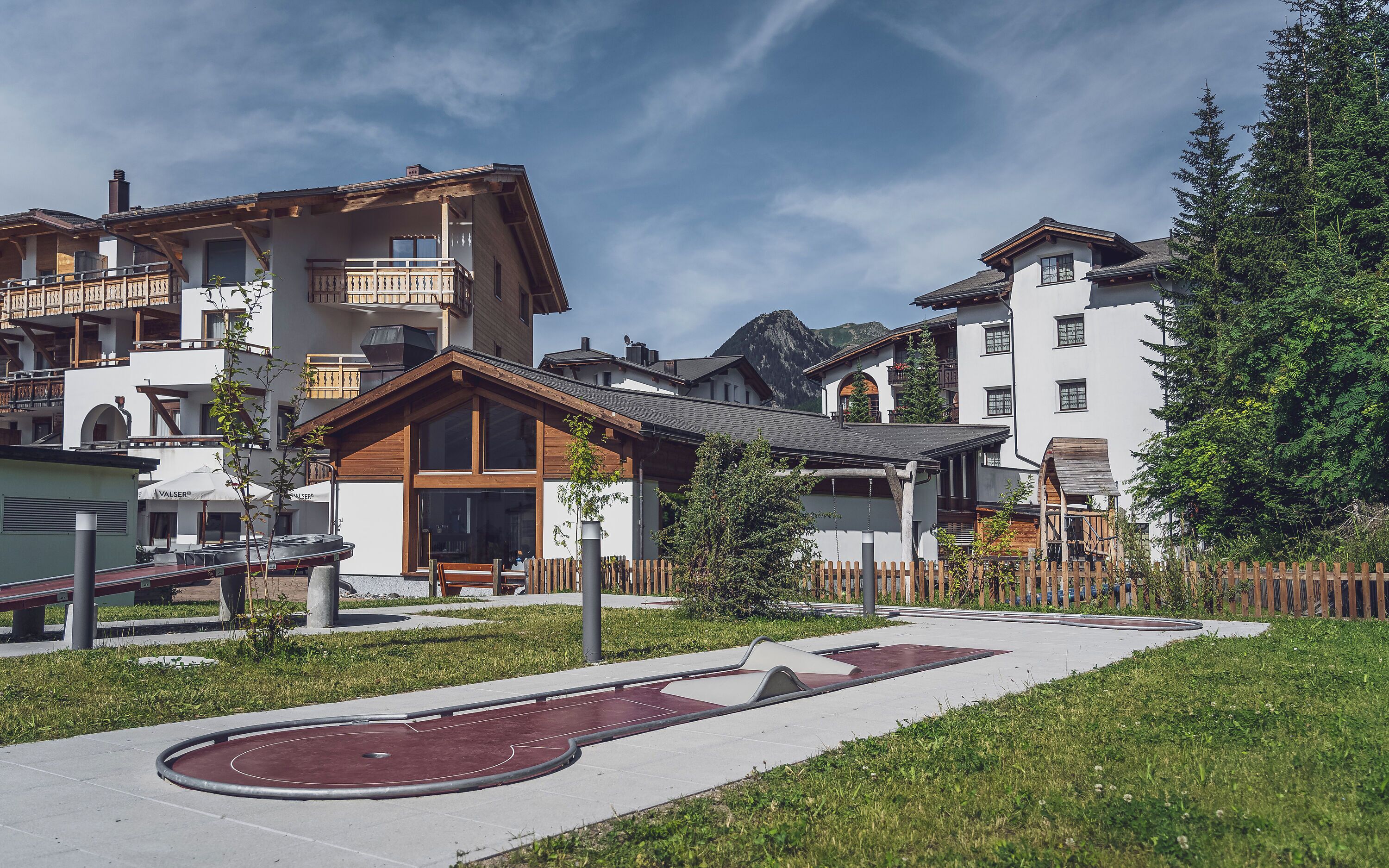 Un quartier résidentiel composé d’immeubles à plusieurs étages, d’un chemin pavé et d’un petit espace vert aménagé en parc.