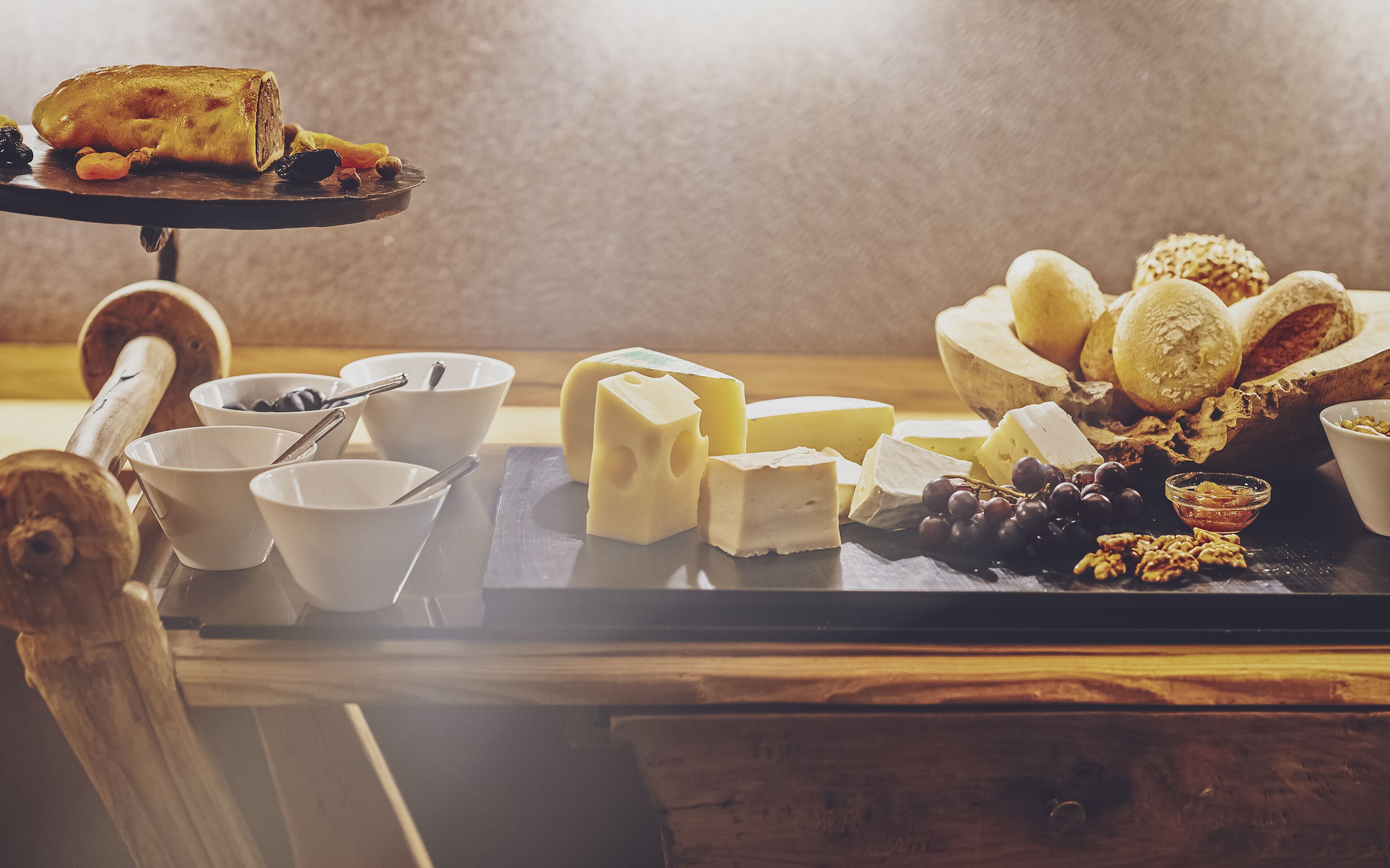 A cheese board with various cheeses, grapes, and nuts on a wooden table.