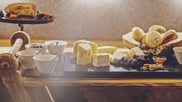 A cheese board with various cheeses, grapes, and nuts on a wooden table.