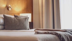 A neatly made bed with two pillows, a bedside lamp, and a wooden headboard. - Hotel Waldhuus Davos (Davos)