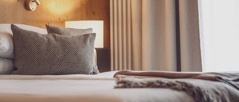 A neatly made bed with two pillows, a bedside lamp, and a wooden headboard.